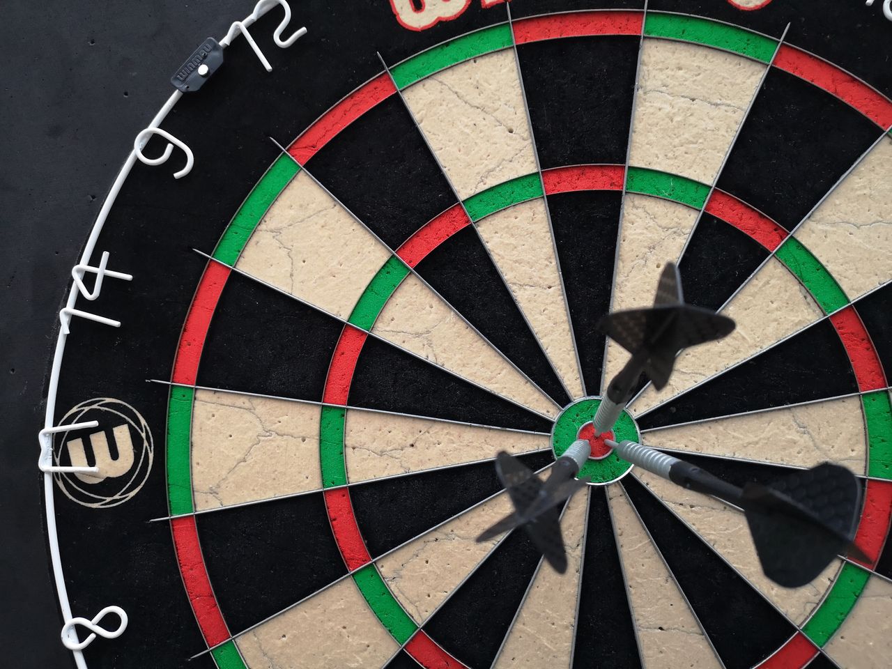 Precision-focused close-up view of darts hitting the bullseye on a dartboard.