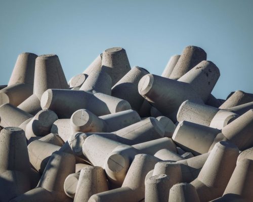 pexels-photo-28352719-28352719 Stacked concrete tetrapods used for wave dissipation at the seashore.